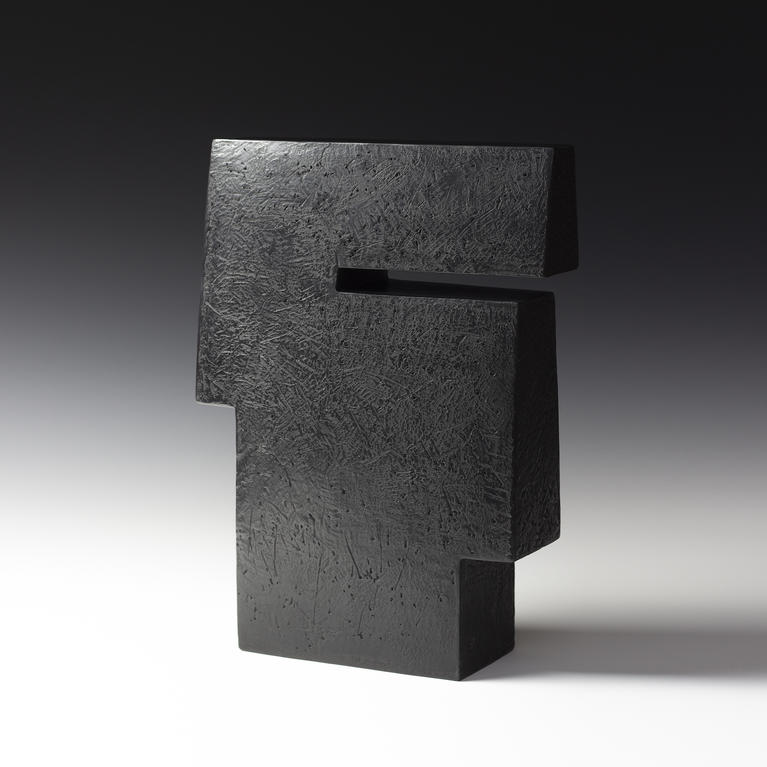 Sculpture aux formes architecturées, noire et polie avec des effets de surface