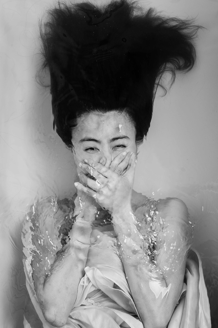 Femme sous l'eau, se bouchant le nez et la bouche